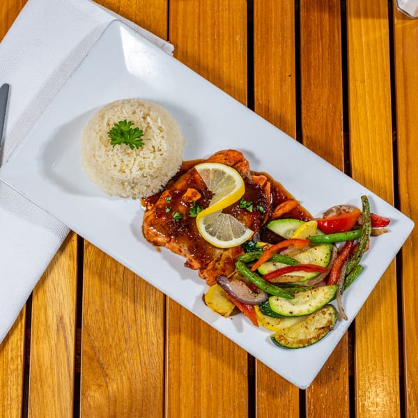 Chloez Cafe's salmon with lemon, rice, and mixed vegetables on a white plate.