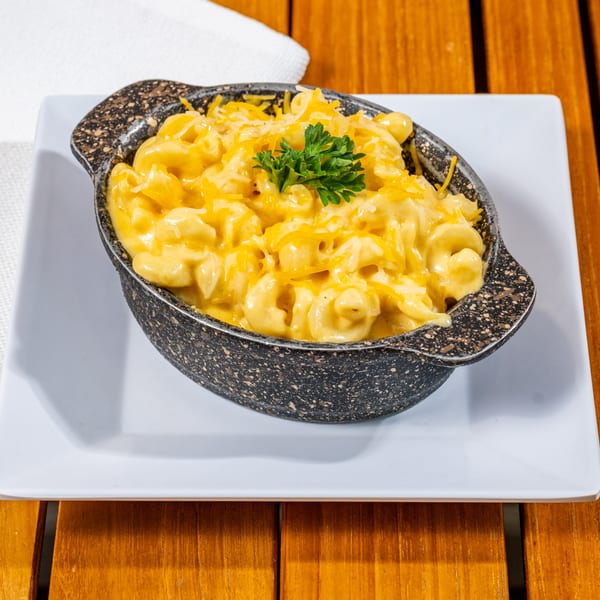 Creamy mac and cheese with shredded cheddar and a parsley garnish in a speckled bowl.