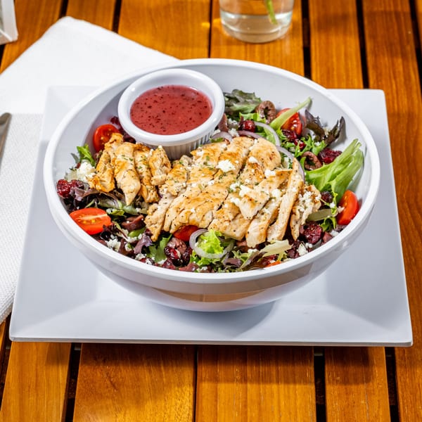 Grilled chicken salad with mixed greens, tomatoes, red onions, feta, and cranberry dressing.