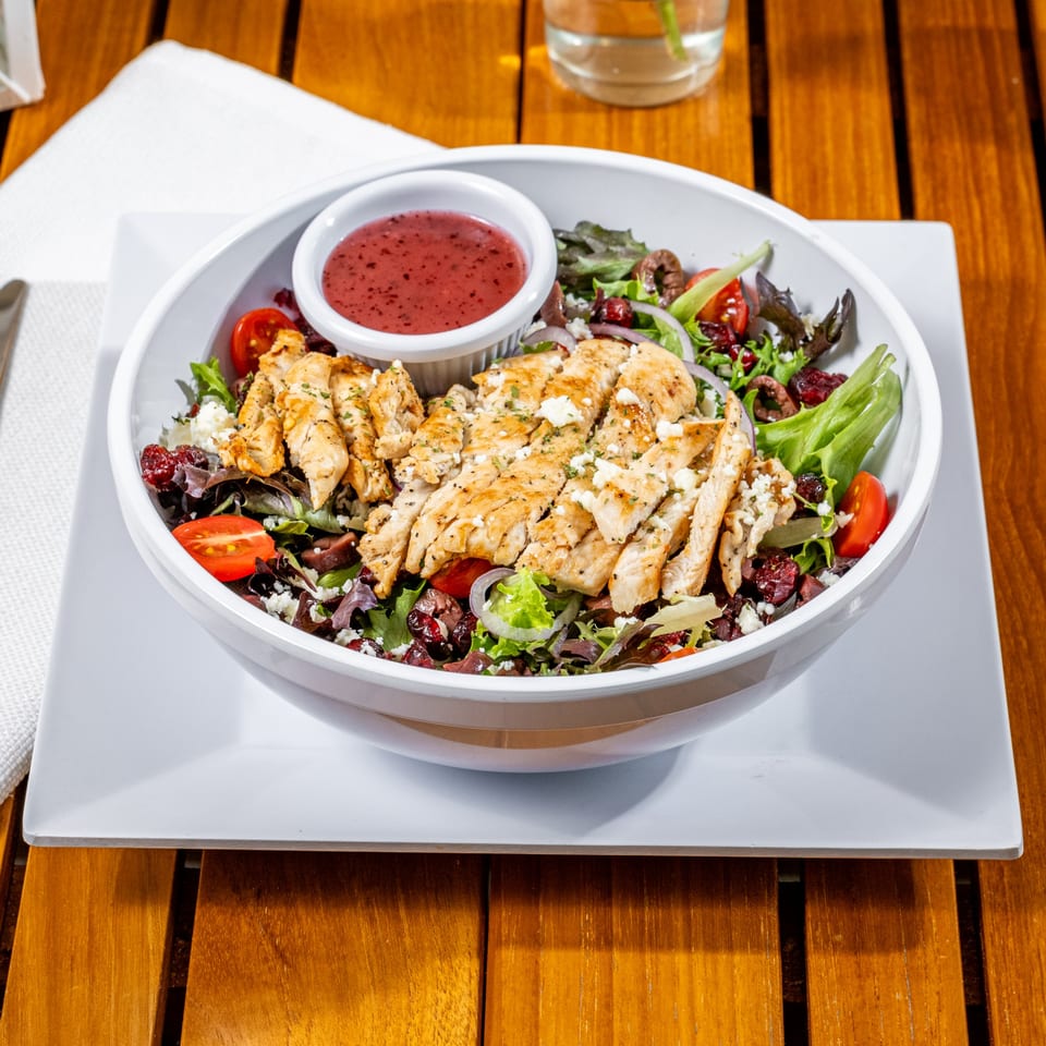 Grilled chicken salad with mixed greens, tomatoes, red onions, feta, and cranberry dressing.